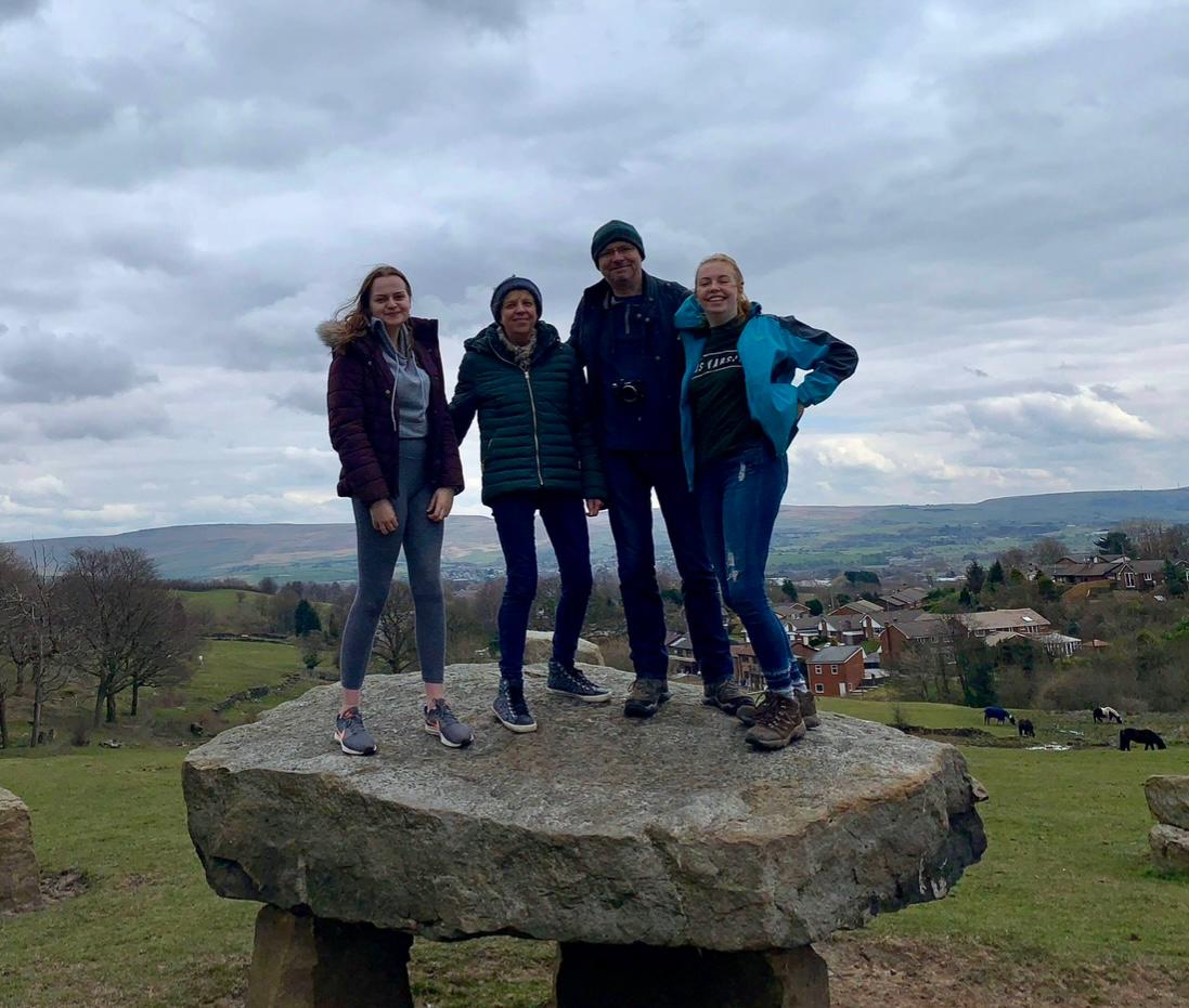 Family having fun stood on a large rock on a hill in the countryside